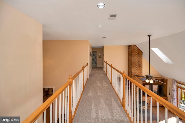 hall with lofted ceiling with skylight, recessed lighting, visible vents, and light colored carpet