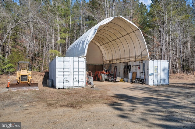 view of outdoor structure featuring a detached carport, an outdoor structure, and driveway