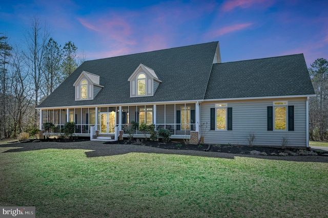 view of front of property with a yard, a porch, and a shingled roof