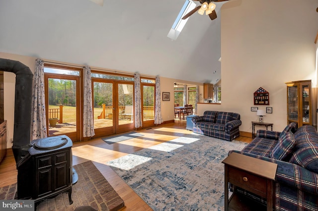 living room with a skylight, baseboards, wood finished floors, french doors, and high vaulted ceiling