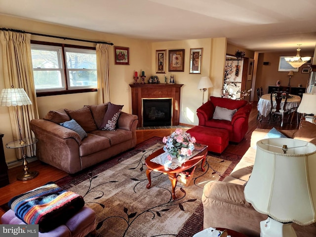 living room featuring a chandelier, a fireplace, and wood finished floors