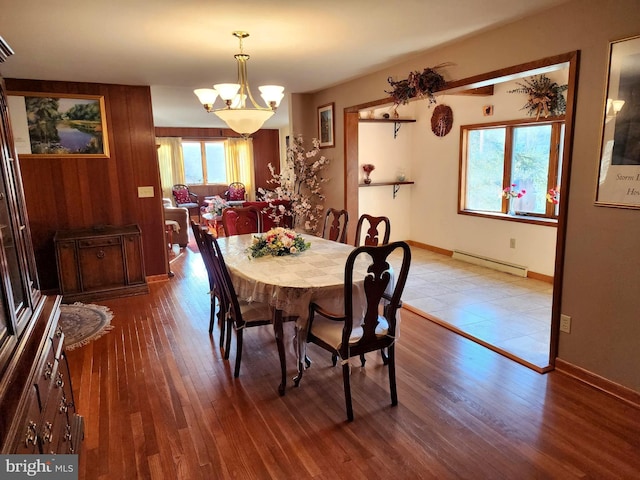 dining space featuring a baseboard heating unit, baseboards, wood finished floors, and a chandelier