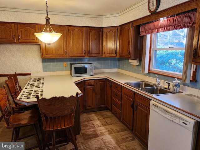 kitchen with a peninsula, white appliances, a sink, and wallpapered walls