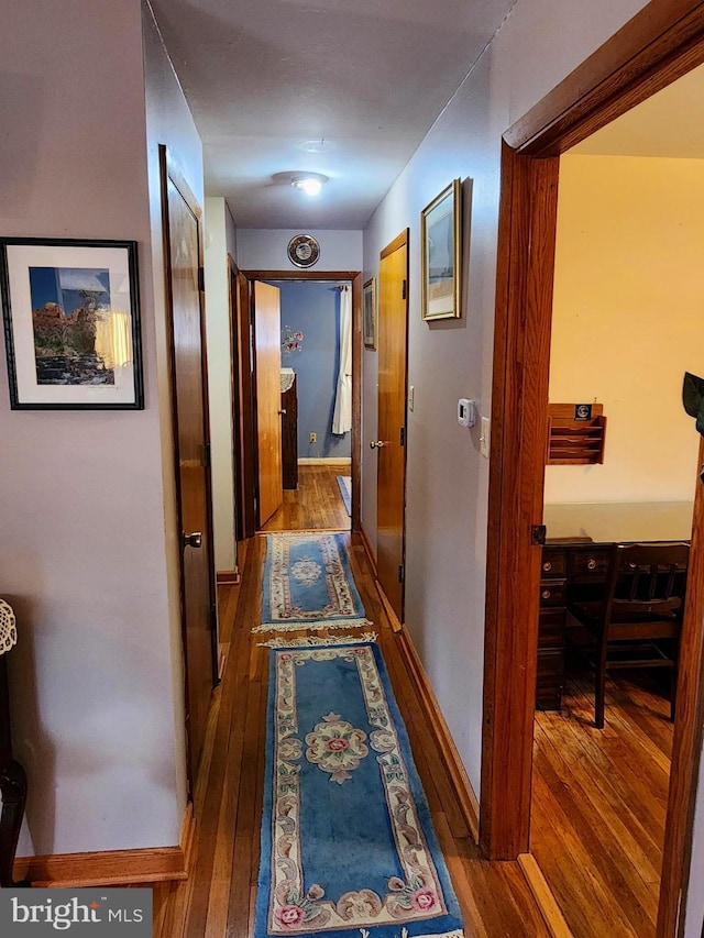 hall featuring baseboards and hardwood / wood-style floors