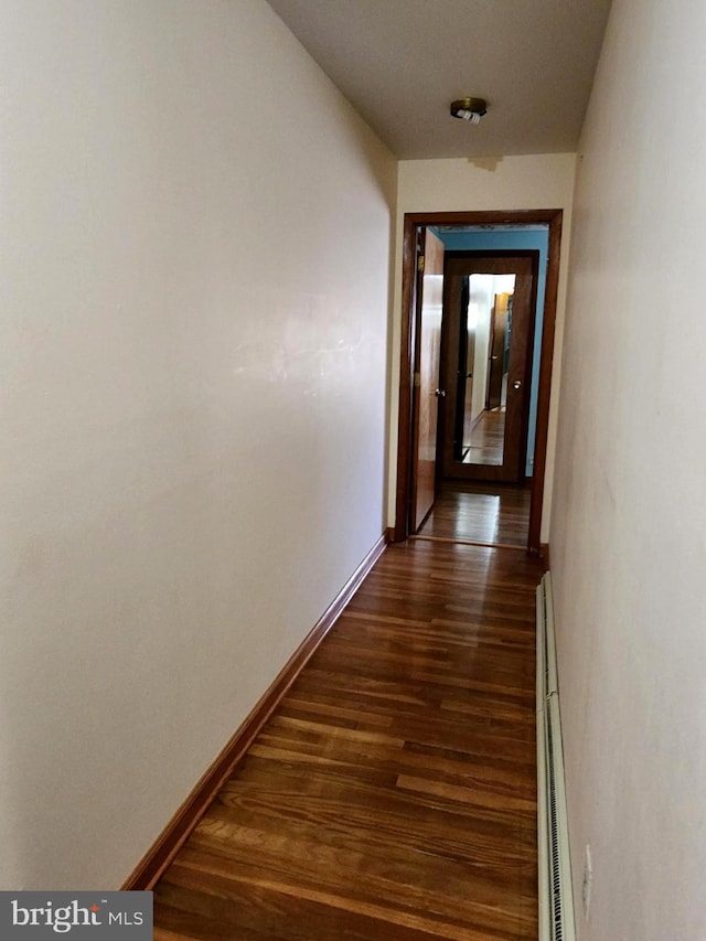 hallway featuring a baseboard heating unit, dark wood-type flooring, and baseboards