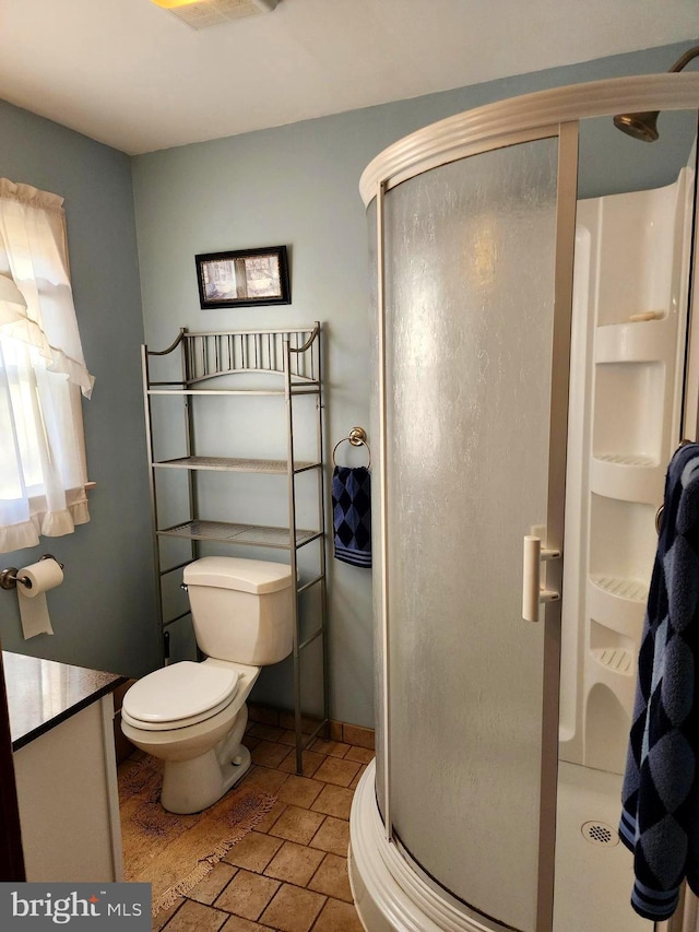 bathroom with a stall shower, baseboards, and toilet