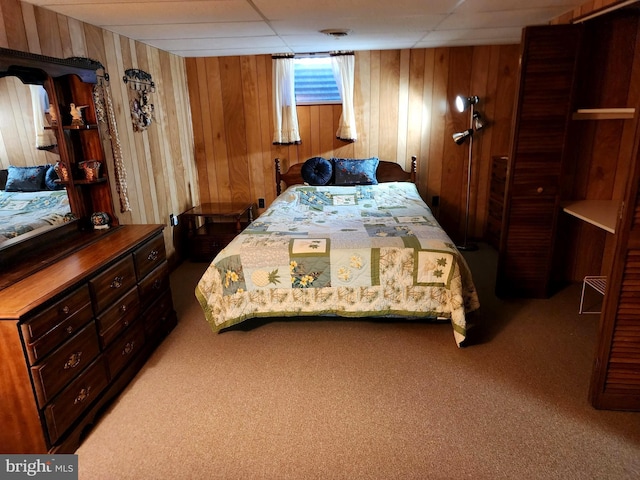 bedroom with a paneled ceiling, carpet, and wooden walls