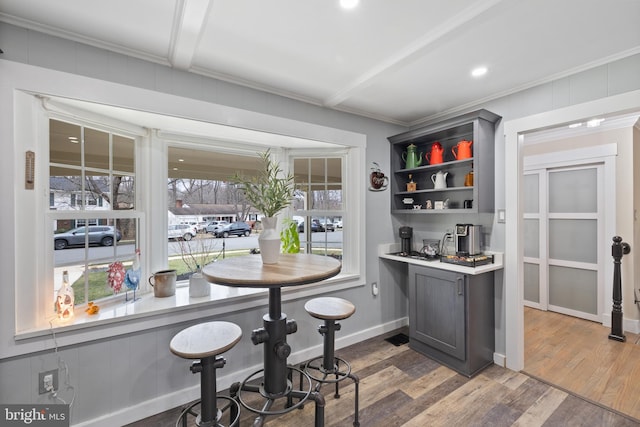 bar with baseboards, crown molding, and wood finished floors