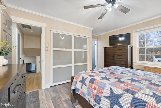 bedroom featuring visible vents, baseboards, a ceiling fan, wood finished floors, and crown molding