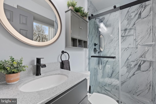 full bath with toilet, vanity, and a marble finish shower