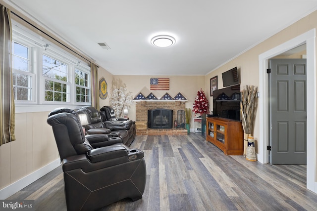 living room featuring a brick fireplace, wood finished floors, and visible vents