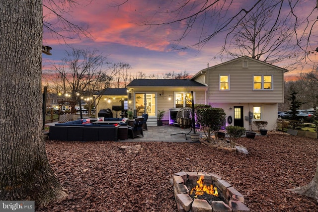 rear view of property featuring an outdoor living space with a fire pit and a patio