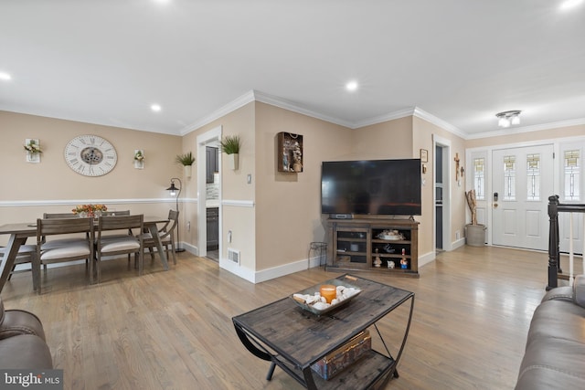 living area with crown molding, visible vents, baseboards, and wood finished floors