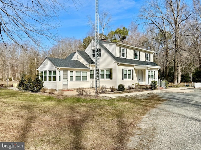 view of front of home with gravel driveway and roof with shingles