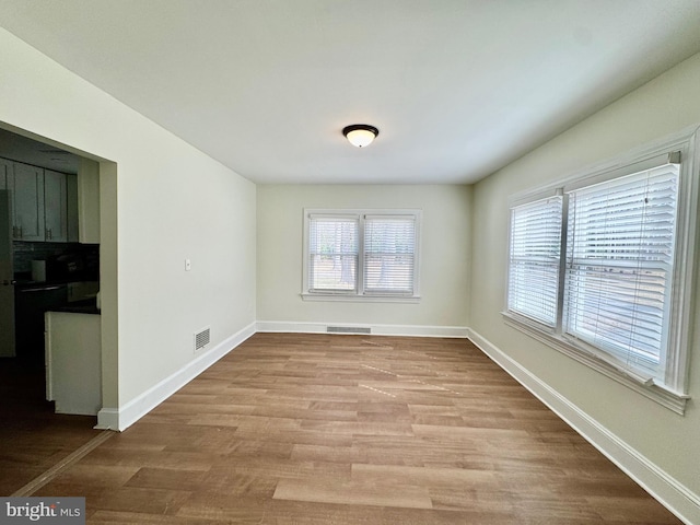 spare room featuring visible vents, baseboards, and wood finished floors