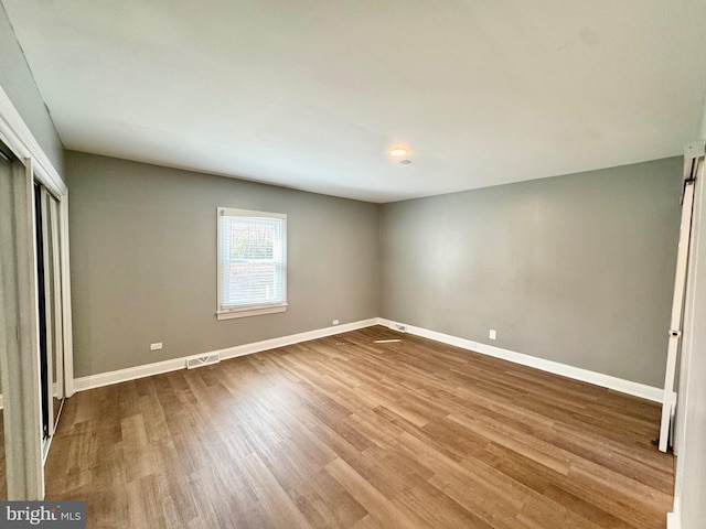 unfurnished bedroom featuring visible vents, wood finished floors, baseboards, and a closet