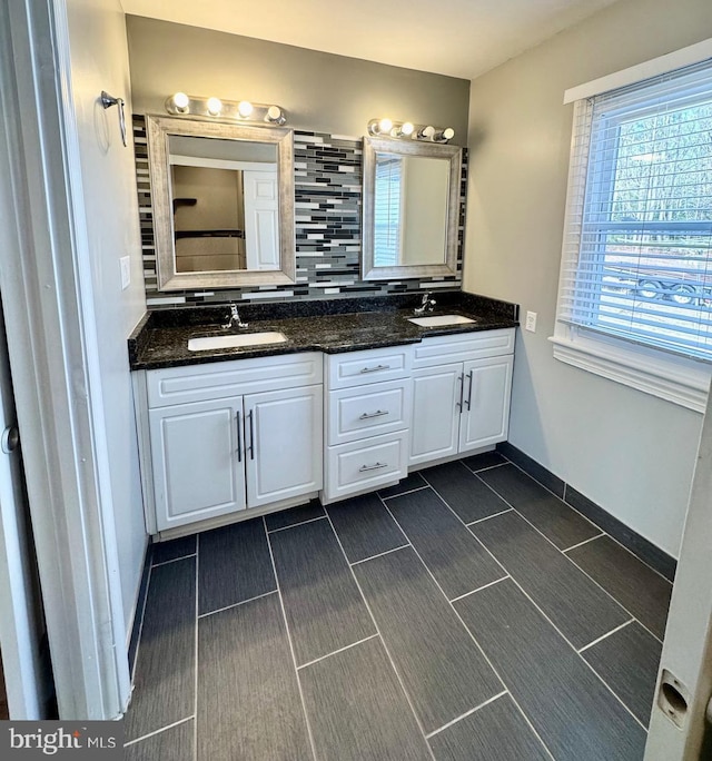 full bath with double vanity, baseboards, tasteful backsplash, and a sink