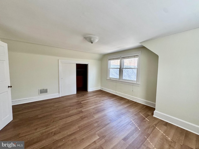 interior space featuring visible vents, baseboards, lofted ceiling, and wood finished floors