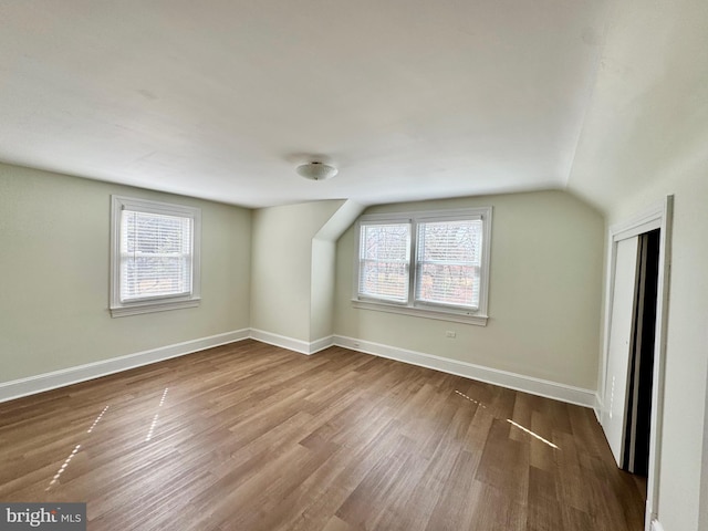 additional living space featuring baseboards, wood finished floors, and vaulted ceiling