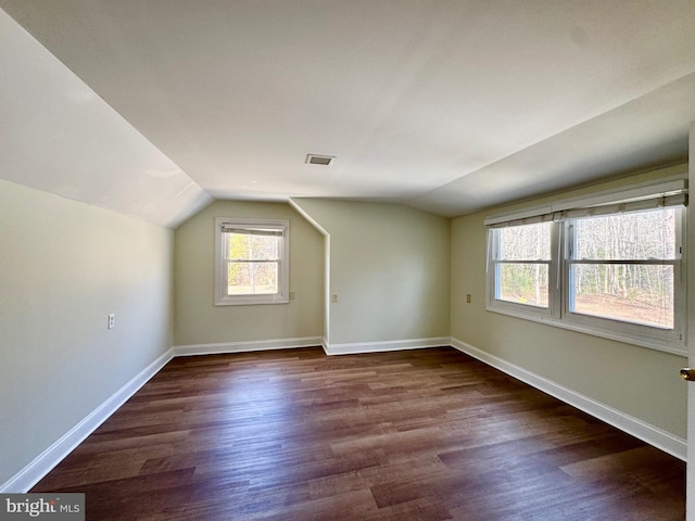 bonus room with lofted ceiling, baseboards, visible vents, and dark wood-type flooring