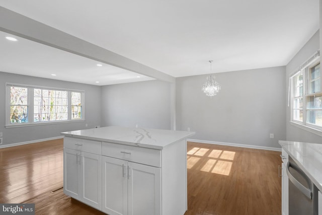 kitchen with light wood finished floors, stainless steel dishwasher, open floor plan, and baseboards