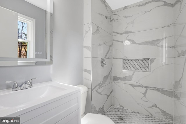 full bath featuring vanity, a marble finish shower, and toilet