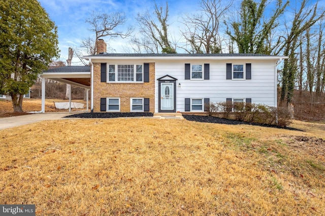 bi-level home with concrete driveway, an attached carport, a chimney, and a front yard