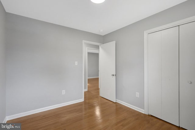 unfurnished bedroom with a closet, baseboards, and wood finished floors