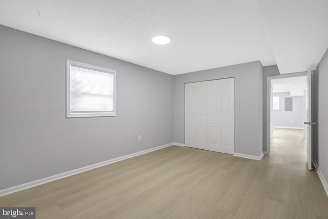 unfurnished bedroom with light wood finished floors, a closet, and baseboards