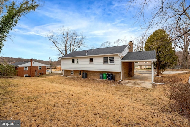 rear view of house featuring brick siding, a chimney, a shingled roof, cooling unit, and an attached carport