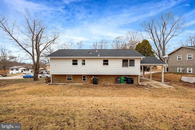 rear view of house with brick siding, a chimney, and central AC unit