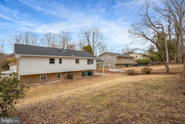 rear view of house with a chimney, central AC unit, and brick siding