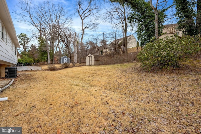 view of yard featuring central air condition unit, a shed, fence, and an outdoor structure