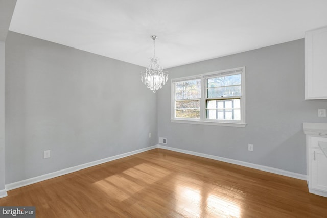 unfurnished dining area featuring a notable chandelier, light wood-type flooring, visible vents, and baseboards