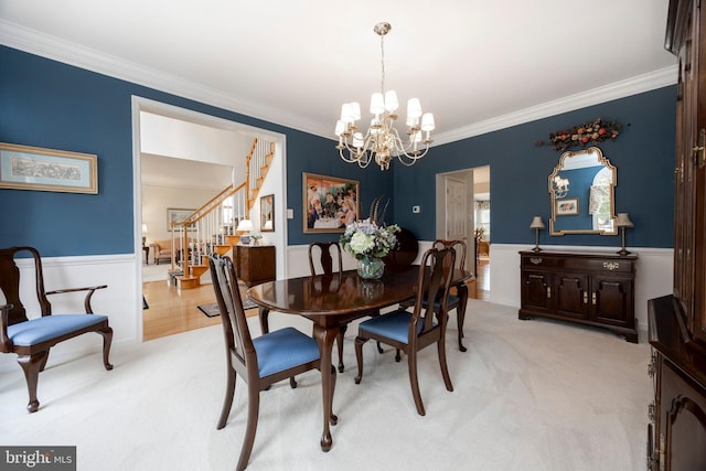 dining space featuring a wainscoted wall, light carpet, crown molding, and stairway