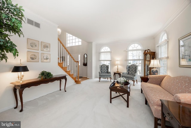 living area featuring carpet flooring, visible vents, stairs, ornamental molding, and plenty of natural light