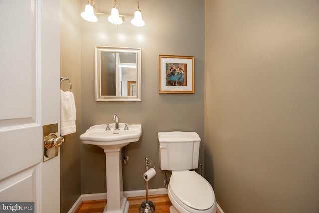 bathroom featuring toilet, baseboards, a sink, and wood finished floors