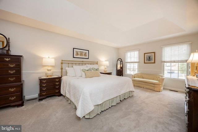 bedroom with carpet floors, a raised ceiling, visible vents, and baseboards