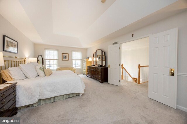 bedroom featuring baseboards, visible vents, a tray ceiling, and light colored carpet