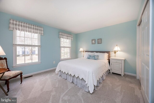 bedroom featuring light carpet, visible vents, baseboards, and a closet