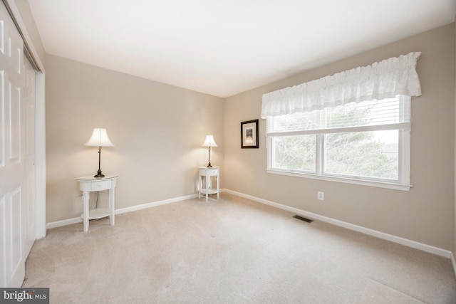 unfurnished room with carpet floors, visible vents, and baseboards