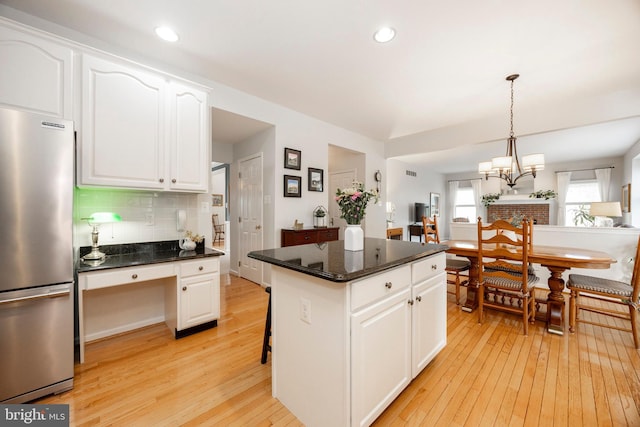 kitchen featuring light wood-style floors, freestanding refrigerator, white cabinetry, and decorative backsplash