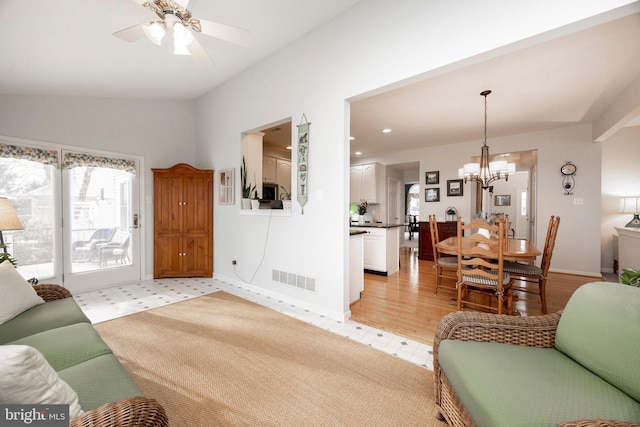 living area with a wealth of natural light, visible vents, baseboards, and ceiling fan with notable chandelier