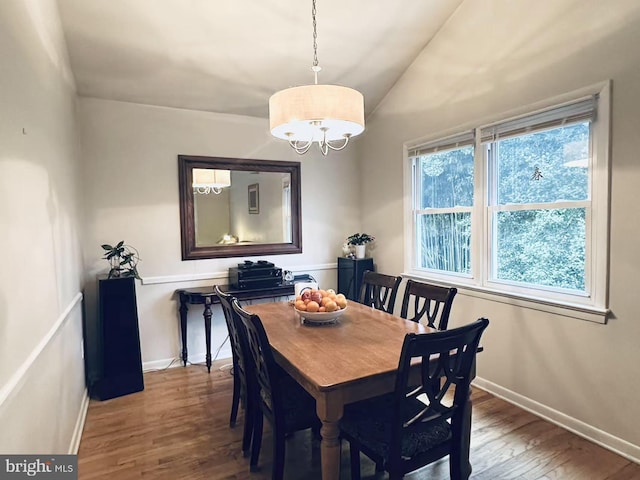 dining space with vaulted ceiling, wood finished floors, and baseboards