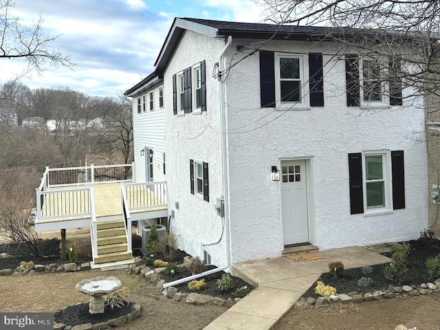 exterior space featuring a wooden deck, stairway, central AC, and stucco siding