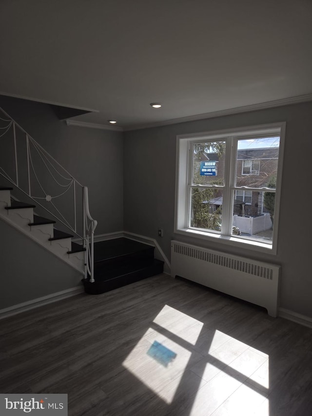 interior space featuring wood finished floors, stairs, radiator, baseboards, and ornamental molding