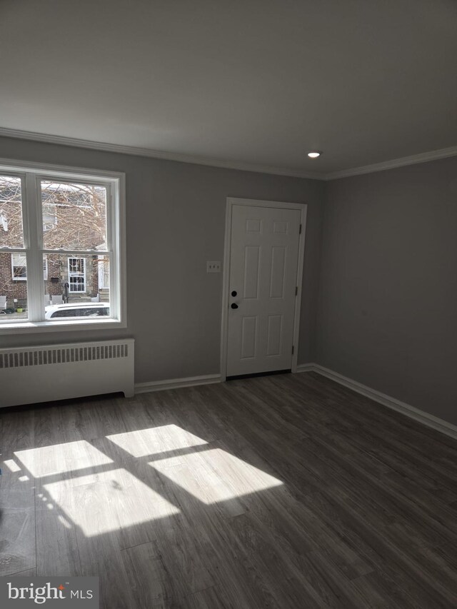 empty room with baseboards, radiator heating unit, and wood finished floors