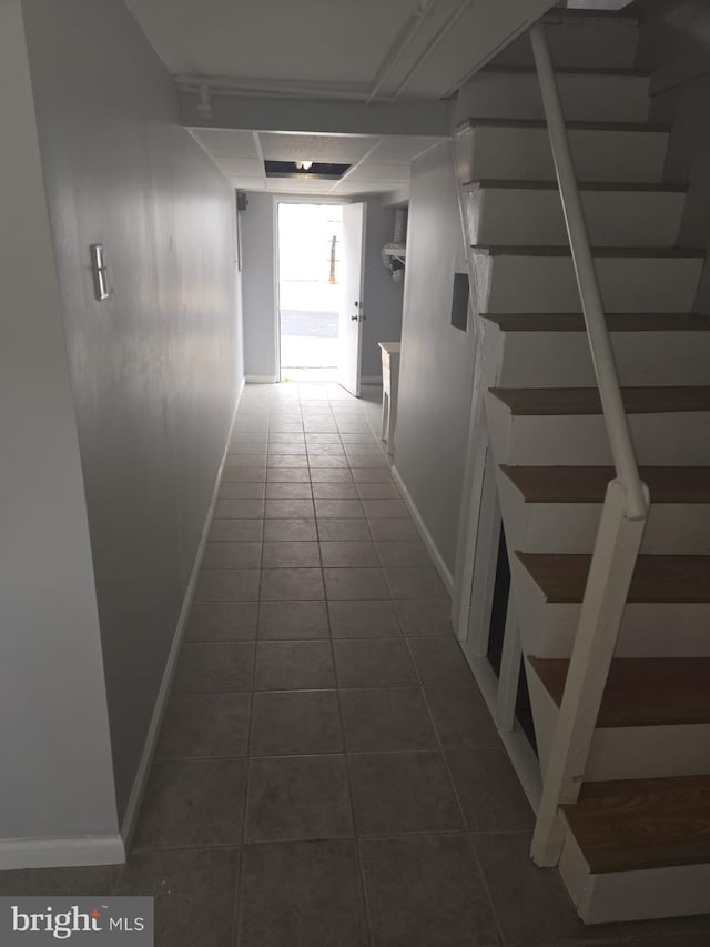 hallway with stairway, baseboards, and dark tile patterned flooring