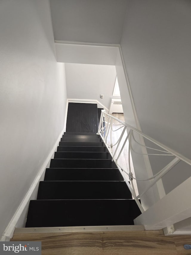 stairs featuring wood finished floors and baseboards