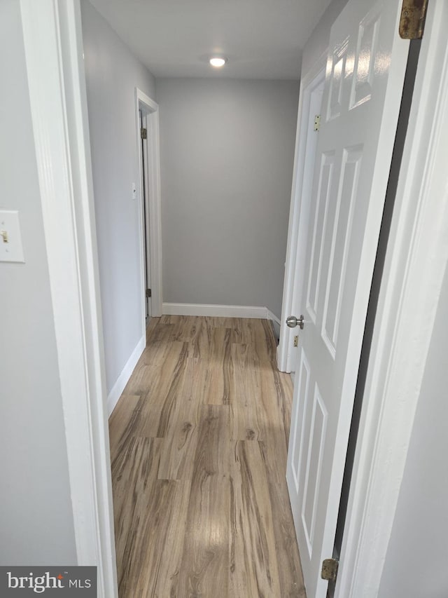 corridor with light wood-style flooring and baseboards